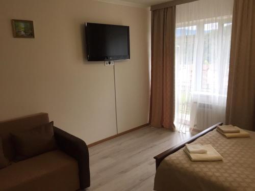 a room with a bed and a couch and a television at Polyana Apart in Polyana