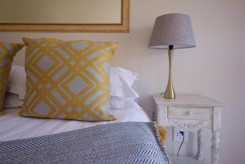 a bed with a yellow pillow and a lamp on a night stand at Cultivar Boutique Hotel in Stellenbosch