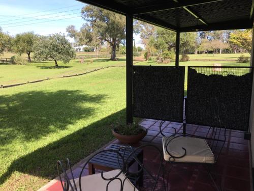 a patio with chairs and a table and a field at Noha Casa de Campo in Colón