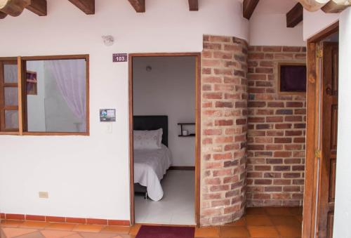 a bedroom with a bed and a brick wall at Cemandy Hostal in Villa de Leyva