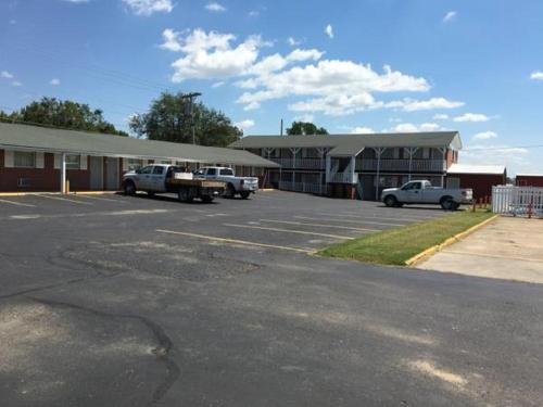 a parking lot with cars parked in front of a building at Guest House Motel Chanute in Chanute
