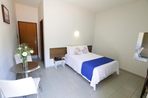 a hotel room with a bed and a table and a chair at Hotel Porto do Sol in Caetité