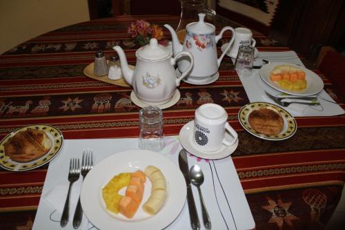 a table with plates of food and cups and utensils at Casa de Luis in Otavalo