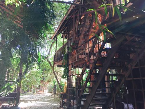 a building with a wooden staircase next to some trees at BaanBooLoo Village in Chiang Mai