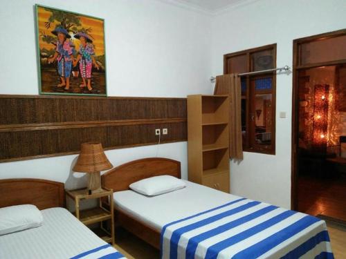 Habitación con 2 camas y lámpara. en Mini Tiga Homestay en Pangandaran