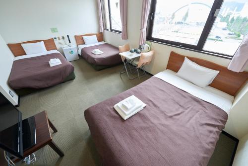 Una habitación de hotel con dos camas y un televisor. en Select Inn Tsuruga, en Tsuruga