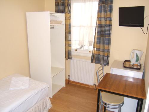 a small room with a bed and a desk and a window at Dolphin Inn - The Lodge in London