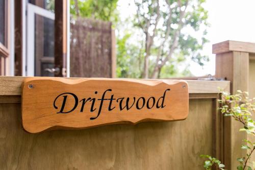 a wooden sign that reads driftwood on a wooden fence at Palm Beach Bungalows in Palm Beach