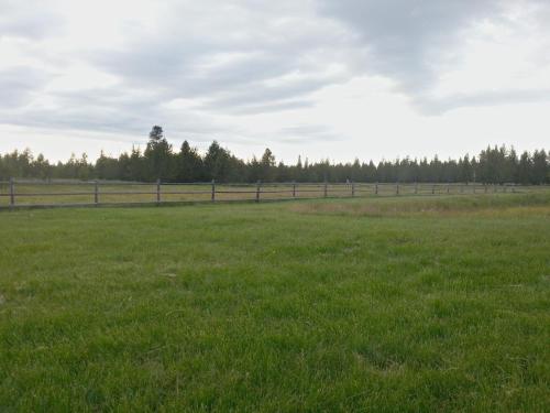 a field of green grass with a fence in the background at DiamondStone Guest Lodges in La Pine