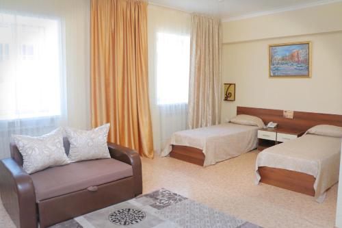 Hotel Zumrat في كاراغاندي: غرفة فندقية بسريرين وكرسي واريكة