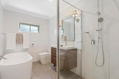 La salle de bains blanche est pourvue d'une baignoire et d'une douche. dans l'établissement Hamptons at The Bay, à Deception Bay