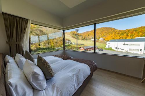 Bett in einem Zimmer mit einem großen Fenster in der Unterkunft Ki Niseko in Niseko