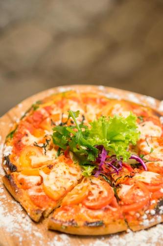 a pizza with greens on top of it on a table at d'primahotel Petitenget Seminyak 2 in Seminyak