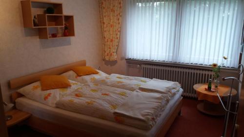 Schlafzimmer mit einem Bett mit weißer Bettwäsche und orangefarbenen Kissen in der Unterkunft Haus am Sonnenhang in Bad Sachsa