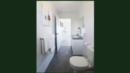 een witte badkamer met een toilet en een wastafel bij Gumnut Getaway BnB in Goolwa North