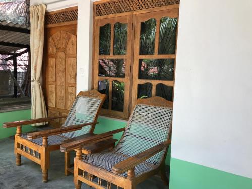 two chairs sitting in a room with windows at Nice Place Beach Hotel in Arugam Bay