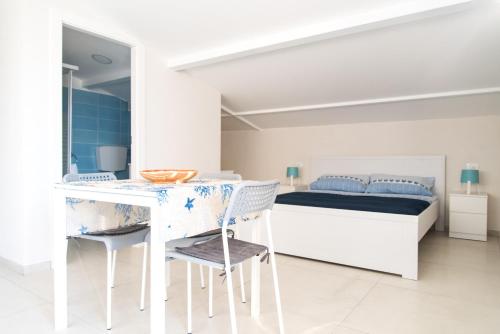 a white bedroom with a bed and a table and chairs at Casa Vacanze Albora in Punta Secca