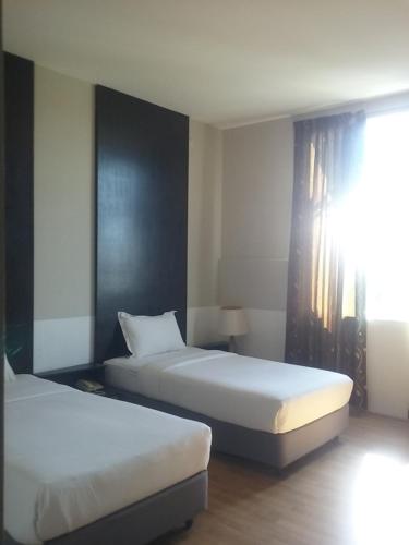 two beds in a hotel room with a window at Ginasuite Hotel in Bandar Seri Begawan