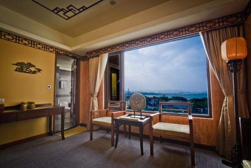 een kamer met een groot raam, een bureau en een stoel bij Sunrise Business Hotel - Tamsui in Tamsui