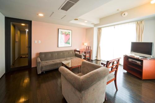 a living room with a couch and a tv at The Residential Suites Fukuoka in Fukuoka