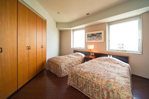 two beds in a room with two windows at The Residential Suites Fukuoka in Fukuoka