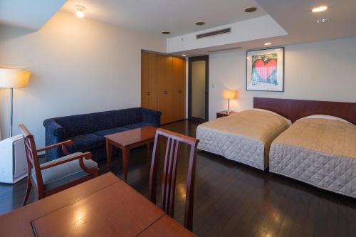 a hotel room with a bed and a couch and a table at The Residential Suites Fukuoka in Fukuoka