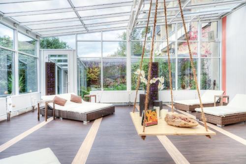 a conservatory with a swing in a room with windows at Hotelpark der Westerwald Treff in Oberlahr