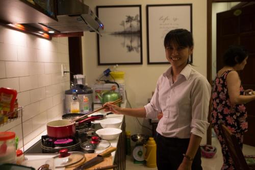 a woman standing in a kitchen preparing food at Riverside Hamlet Homestay & Villa in Hoi An