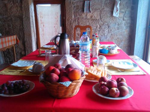 a table with plates of fruit on a red table cloth at Retiro Da Avo Lídia - Turismo Rural in Mendiga