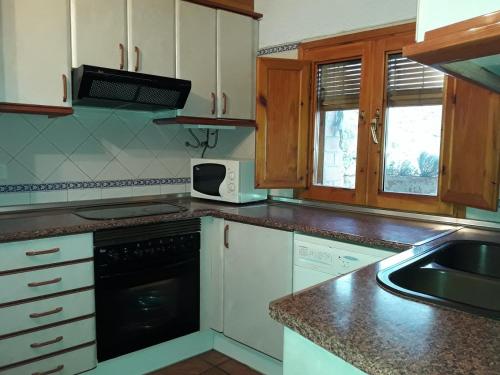 a kitchen with white cabinets and a black appliance at Pati Curreu in Palanques