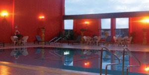 a large swimming pool in a building with chairs at Hotel Grand Continental Kuantan in Kuantan