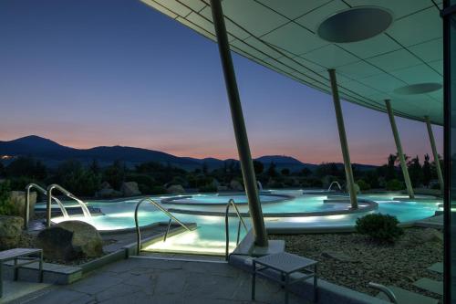 une grande piscine avec un coucher de soleil en arrière-plan dans l'établissement Hôtel Barrière Ribeauvillé, à Ribeauvillé