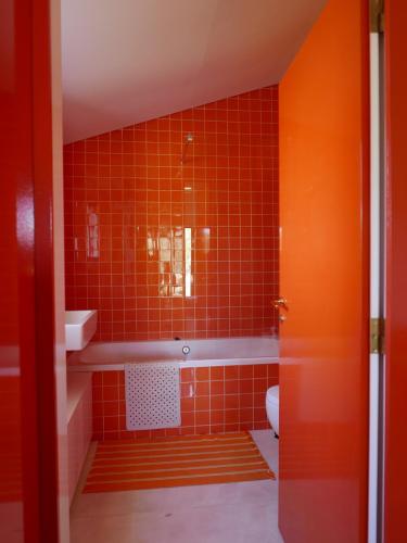 an orange bathroom with a tub and a toilet at Casa do Vale da Terra Negra in Vila Nova da Baronia