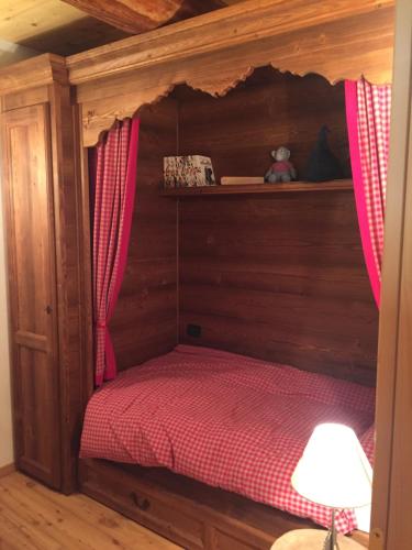 a small bed in a wooden room with a canopy at Chalet nel cuore delle Dolomiti in Falcade