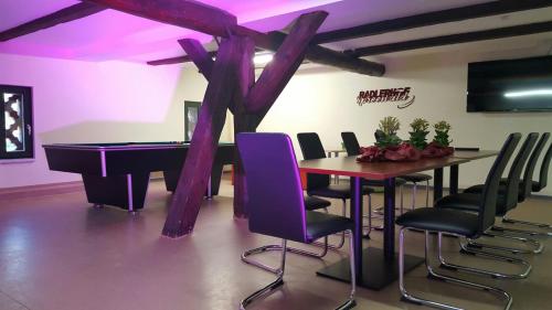 a room with a ping pong table and purple chairs at Radlerhof Spreewald in Kolkwitz