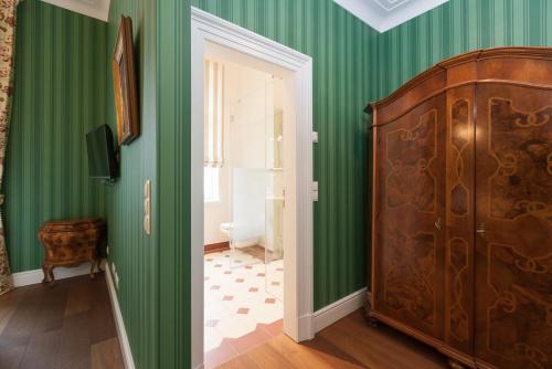 ボホルトにあるRooms GUT HEIDEFELDの緑の壁と大きな木製キャビネットが備わる客室です。