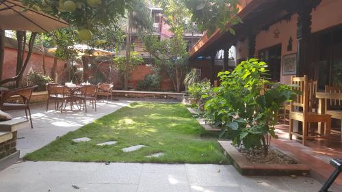 帕坦精品历史之家旅馆的庭院里有草坪和植物的花园