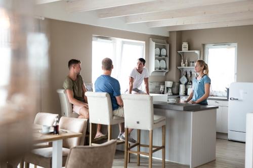 a group of people sitting at a counter in a kitchen at Beach Apartments Heiligenhafen in Heiligenhafen