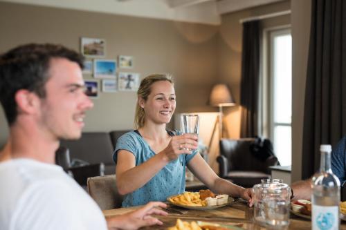 a woman sitting at a table with a glass of wine at Beach Apartments Heiligenhafen in Heiligenhafen