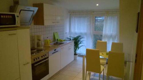 a kitchen with white cabinets and a table and chairs at Sarah klein aber fein in Wellesweiler