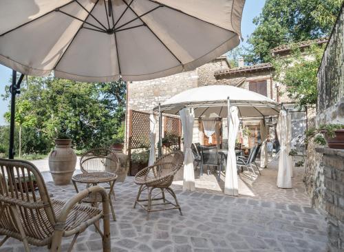 a patio with two umbrellas and chairs and a table at B&B Cantico Delle Creature in Assisi