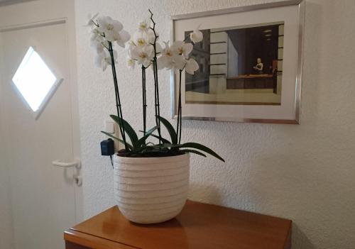 a white vase with white flowers on a table at Haardblick in Flaesheim