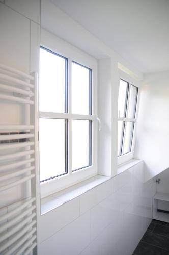 a bathroom with white walls and two windows at Aaltine 3 in Bad Bentheim