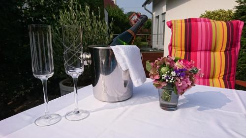 a table with two wine glasses and a vase of flowers at Haardblick in Flaesheim
