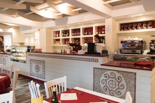 a restaurant with a counter and a woman preparing food at Hotel du Grand Parc in Gex