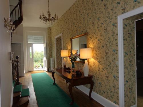 a room with a table with two lamps and a green rug at La Maison Ribotteau in LʼIsle-Jourdain