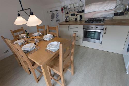 a kitchen with a wooden table and chairs and a kitchen with a stove at Blue Bell Cottage in Ollerton