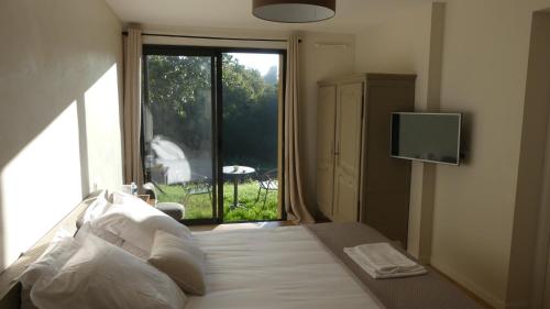 a bedroom with a bed with a window and a television at Domaine de Tréouzien in Plouhinec