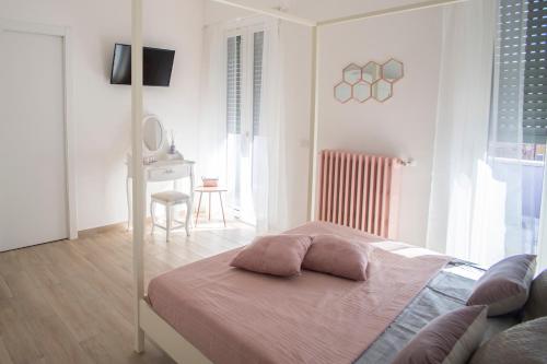 Habitación blanca con cama con almohadas rosas. en La Maison Extravagante, en Saronno