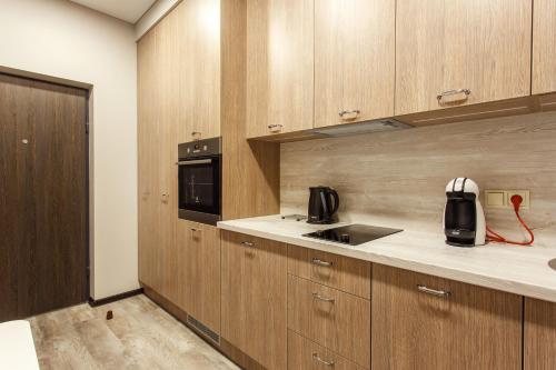 a kitchen with wooden cabinets and a black appliance at Old Town Trio Apartments in Vilnius